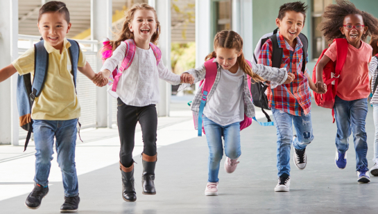 Elementary school students running while holding hands