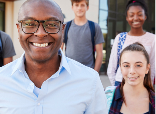Teacher with high school students standing behind